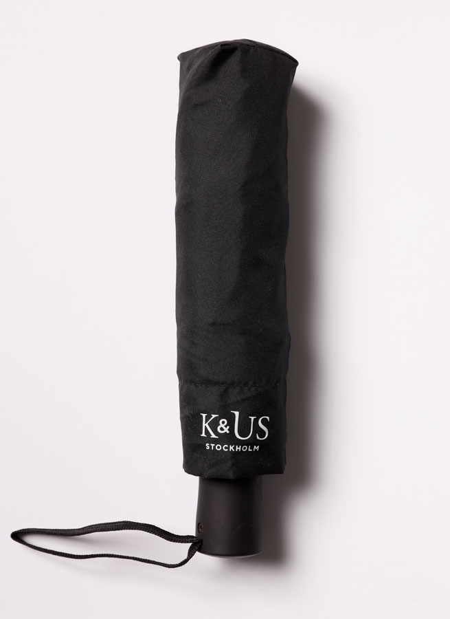 Paraply svart K&US. Hopfällbart paraply. Svart med röd smal kant längst ut.