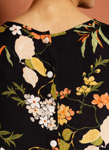 Mönstrad tunika på svart botten. Blommönster, trekvartsärm, dekorativa knappar bak. K&US