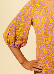 Gul klänning med lila, orange blommor. V-ringad, fastsydd omlott, puffärm. K&US unik design